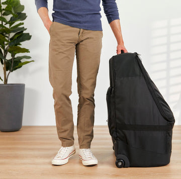 image of a person standing next to and holding the top handle of the Roam Padded Roller Backpack